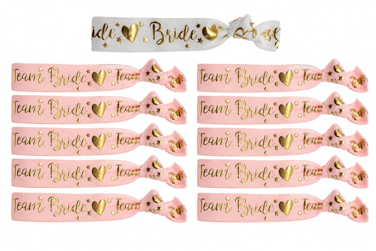 Eén wit Bride armbandje en tien roze Team Bride armbandjes met gouden tekst, hartjes en sterren.
