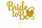 Gouden glittertaarttopper met ‘Bride to Be’ en een hart op een houten prikker.