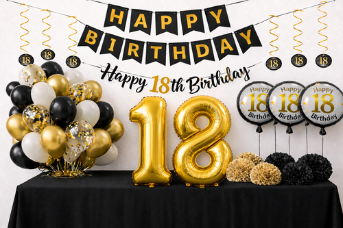 Verjaardagsversiering voor 18 jaar met gouden cijferballonnen, zwarte en gouden slingers, ballonnen en pompoms op een zwarte tafel.